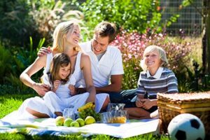 glueckliche familie picknickt in einem schoenen gruenen garten